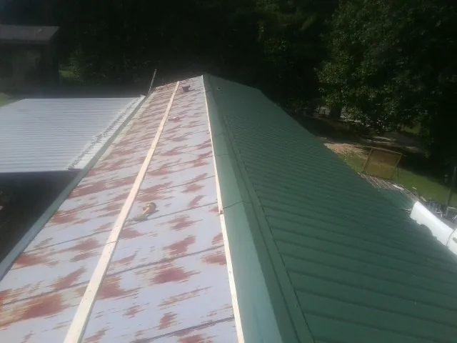 Old rusted panels beside newly installed green metal roofing — Wind Damage Roof Repair by Roofing Brothers in Louisburg