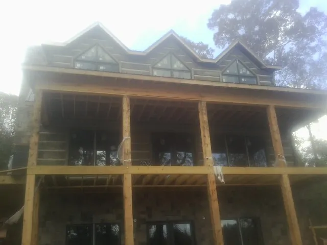 Dormers and porch framing on a large log home under construction — Roof Coating work by our crew in Louisburg