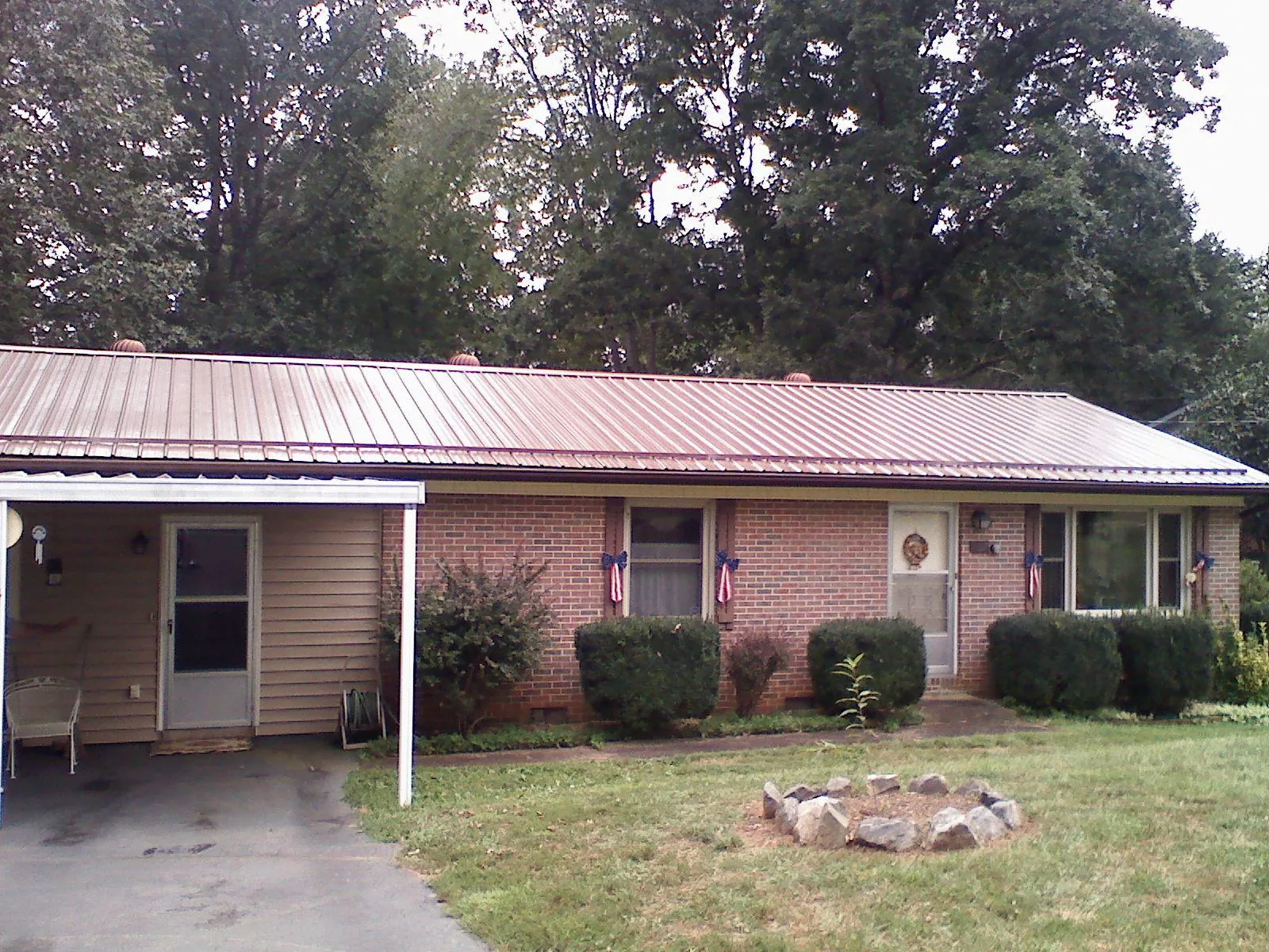 Bronze metal roof and carport on a brick ranch home — Roof Repair work by our crew in Louisburg